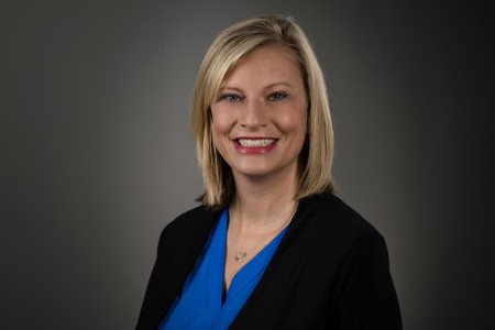 Kristen Brown, a woman wearing plain blue top with black blazer, short straight blond hair and big smile