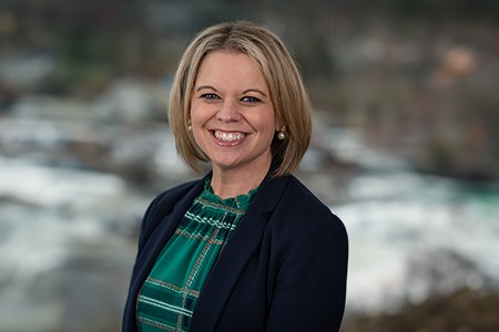 Shannon Nally, a woman wearing a green checked top with blue blazer, pearl earrings, short blond hair and big smile